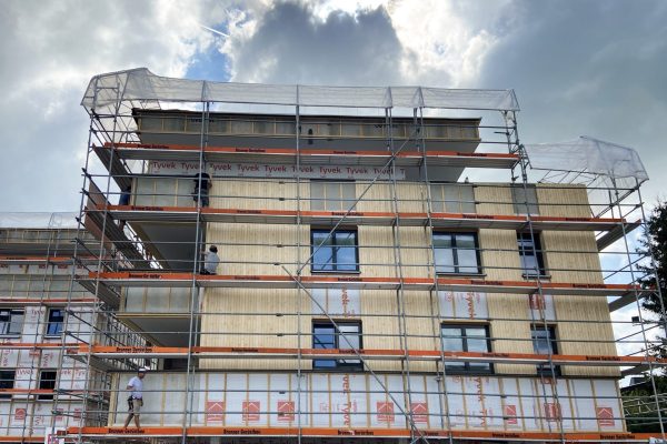 Baustelle Froschweg, Gerüst an Fassade, Arbeiter bringen Holzfassade an