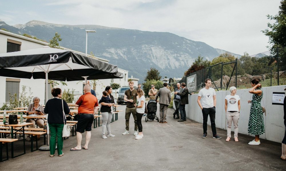 Gäste versammeln sich für ZIMA Sommerfest in Schwaz auf dem Vorplatz des ZIMA Projekts Minkuswiese