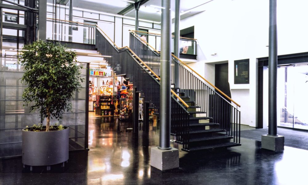 Innen Foyer Lünserseefabrik in Bürs, Architekturmerkmale Industrie modern interpretiert, schwarze Geländer und Treppen in Kombination mit Glasbrüstungen