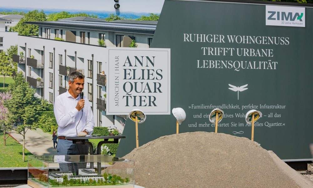 Mag. Alexander Nußbaumer (Vorstand CEO, Inhaber der ZIMA) mit Mikrofon und Werbeplane im Hintergrund, präsentiert Annelies Quartier